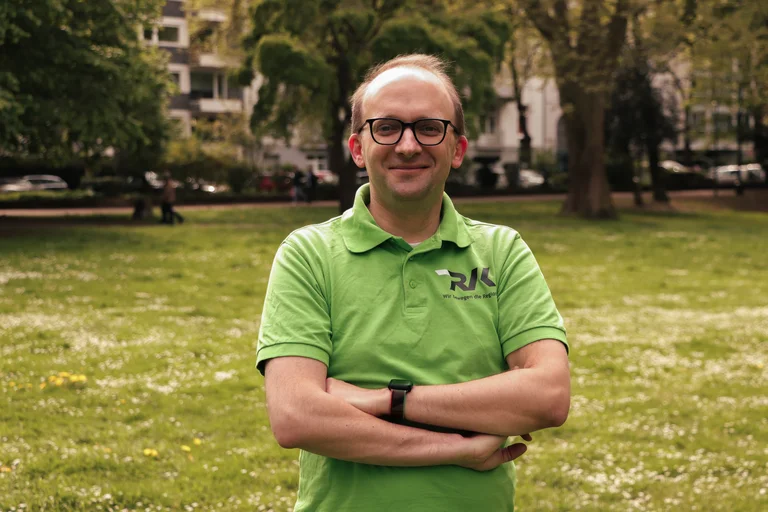 Portrait eines Mannes im RVK-Shirt draußen im Park.