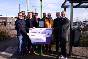 Das Bild zeigt mehrere Menschen an einer digitalen Haltestelle