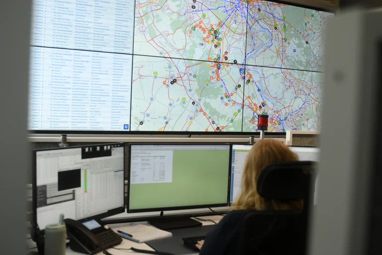 Das Bild zeigt eine Mitarbeiterin der Leitstelle, die vor der großen Videoleinwand sitzt