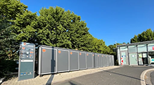 Graue Fahrradboxen in Bensberg vor Bäumen und blauem Himmel