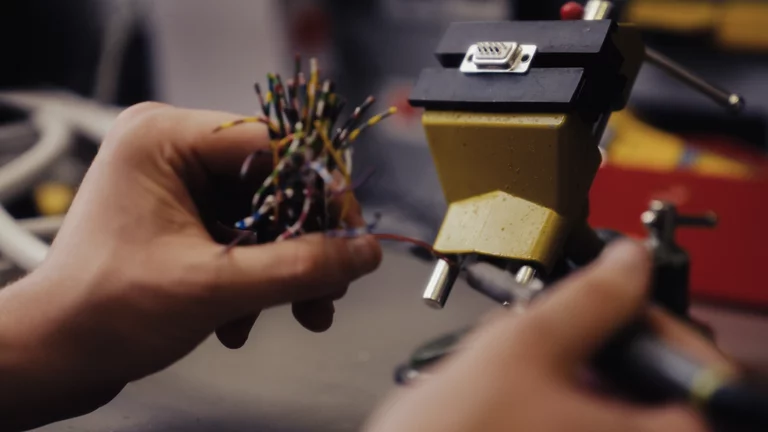 Zwei Hände, welche in der Werkstatt gerade am bauen technischer Anschlüsse sind