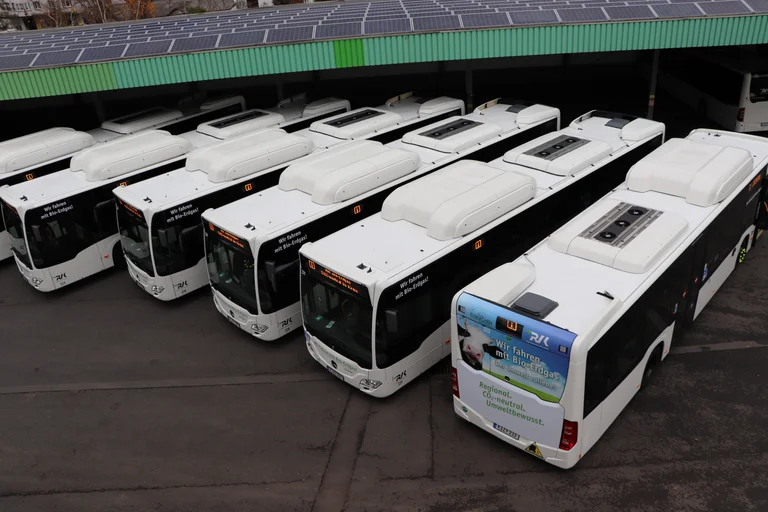 Das Bild zeigt mehrere Bio-Methan-Busse, die nebeneinander stehen