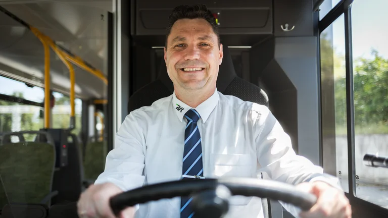 Lachender Busfahrer hinterm Steuer eines Busses