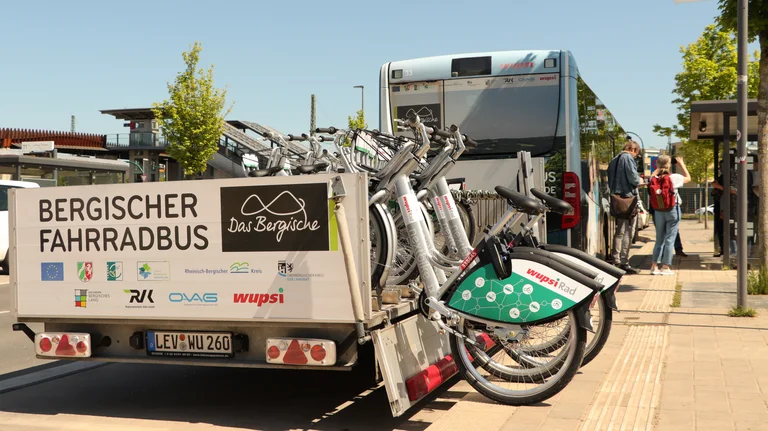 Fahrradanhänger von hinten, gespannt an die Anhängerkupplung des Fahrradbusses, darauf stehen e-Bikes