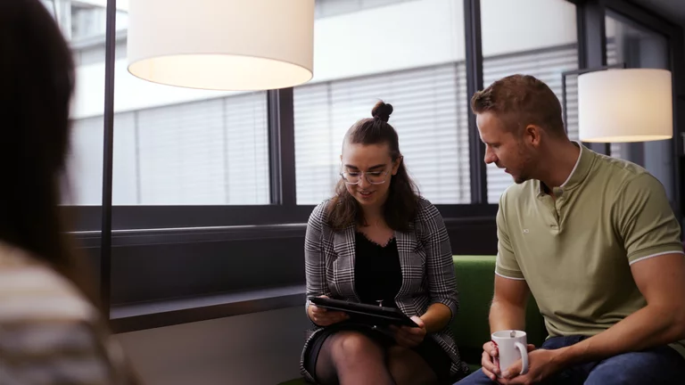 Gespräch zwischen Mitarbeitenden und Auszubildender, welche sich gegenüber auf zwei Couches sitzen.