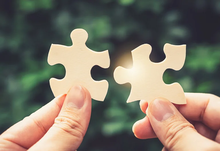 Zwei Hände die ineinandergreifende Puzzleteile halten