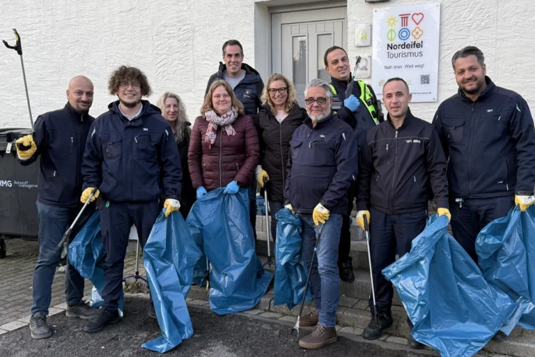 Auf dem Bild sind mehrere Menschen, die in ihren Händen Müllzangen und Müllsäcke halten.