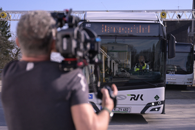 Das Bild zeigt einen Kameramann von hinten, der einen Bus der RVK filmt