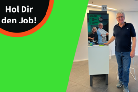 Das Bild zeigt einen Mann, der auf einem Bewerbungsstand steht. Daneben steht links in der Ecke "Hol dir den Job!"