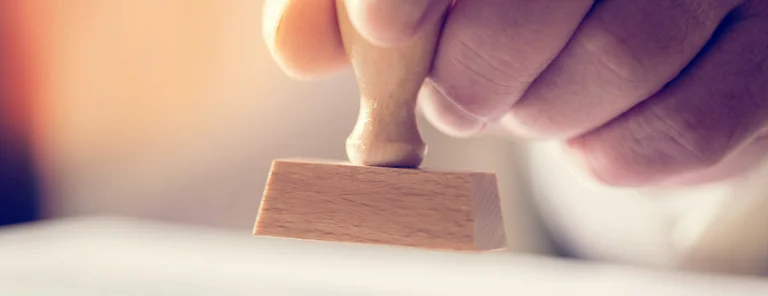 Hand mit offiziellem Stempel in der Hand auf Papier drückend