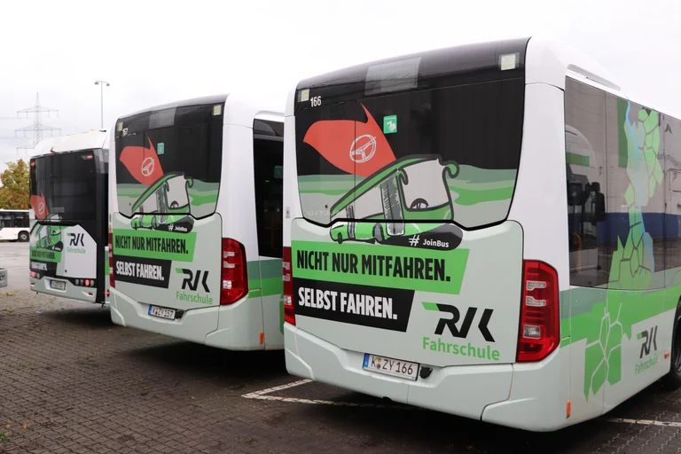 Das Bild zeigt die Hecks von drei Fahrschulbussen mit der Aufschrift "Nicht nur mitfahren. Selbst fahren."