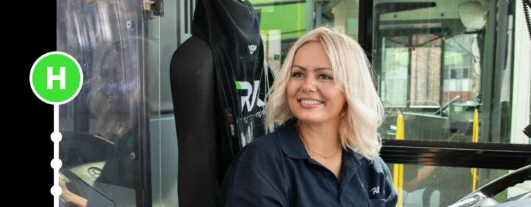 Das Bild zeigt eine blone Frau, die in einem Bus sieht und lächelt