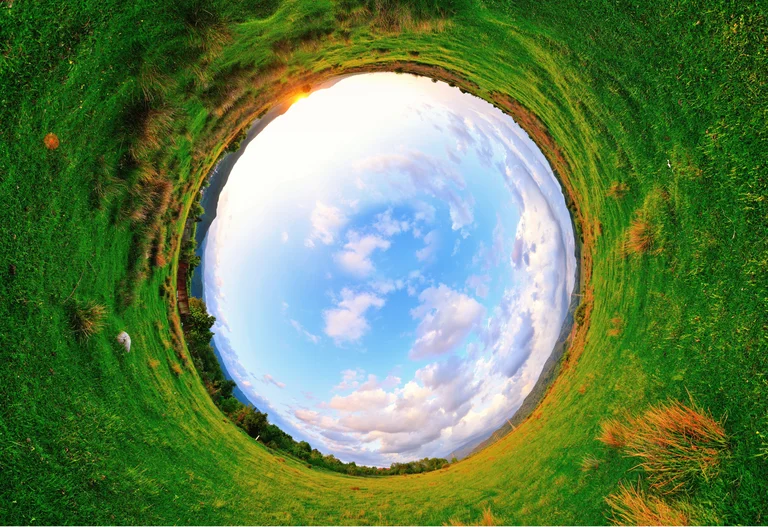 Eine Weitwinklinge Aufnahme, in welcher der Himmel ein Kreis wurde, drumherum grünes Gras einer Wiese