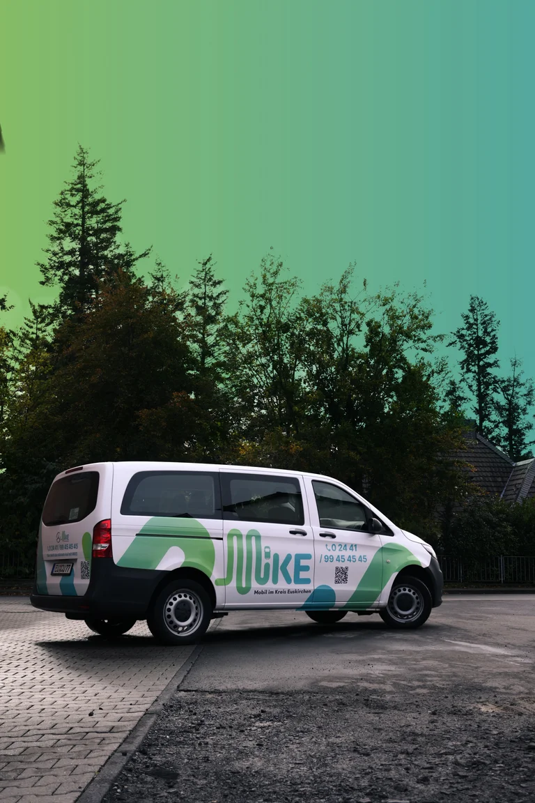 Großraum-Auto auf der Straße für On-Demand-Verkehr mit Folierung MiKE (Mobil im Kreis Euskirchen).